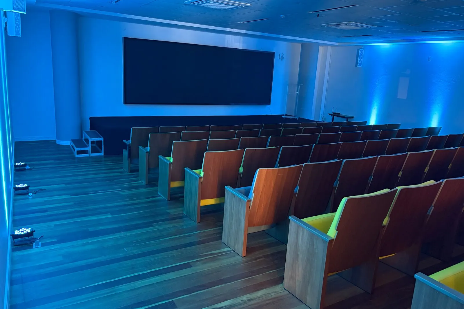 Auditório do Elume com iluminação azul e telão, preparado para um evento