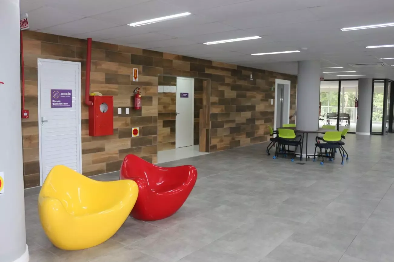 Área de convivência no térreo da sede do Elume, com poltronas amarela e vermelha